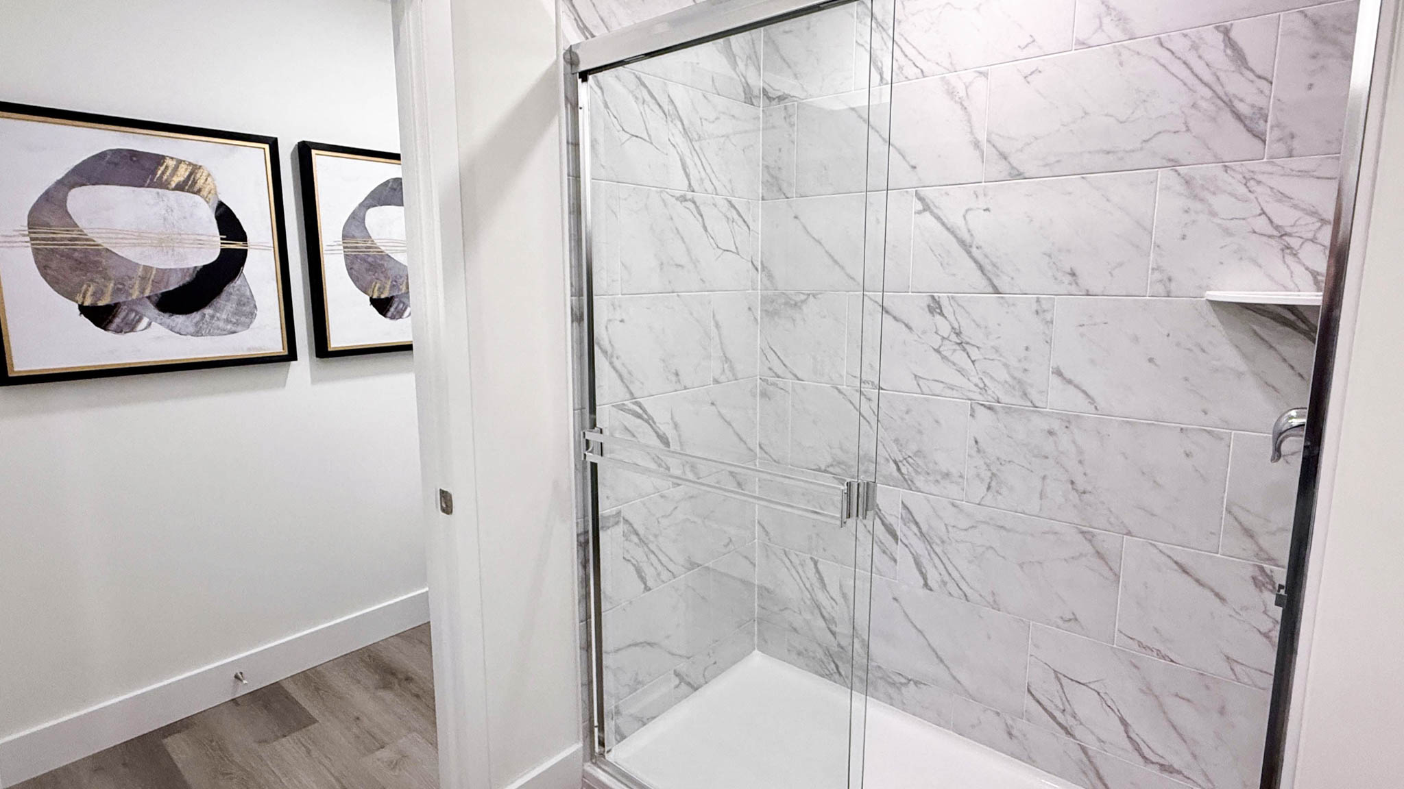 primary shower with tile and sliding glass door