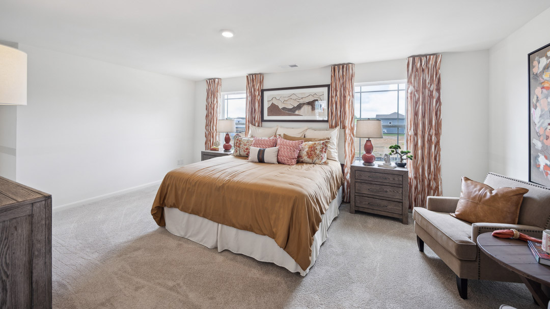 Other view of primary bedroom, 2 single windows, 2 nightstands, and 2 accent chairs off to the side.