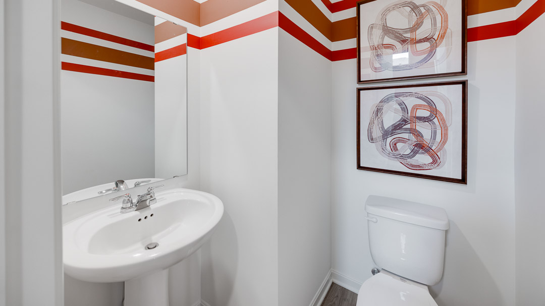 First floor half bathroom with a pedestal sink and commode.