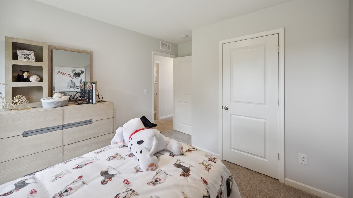 Upstairs spare bedroom with bed, closet door, dresser, and entry door