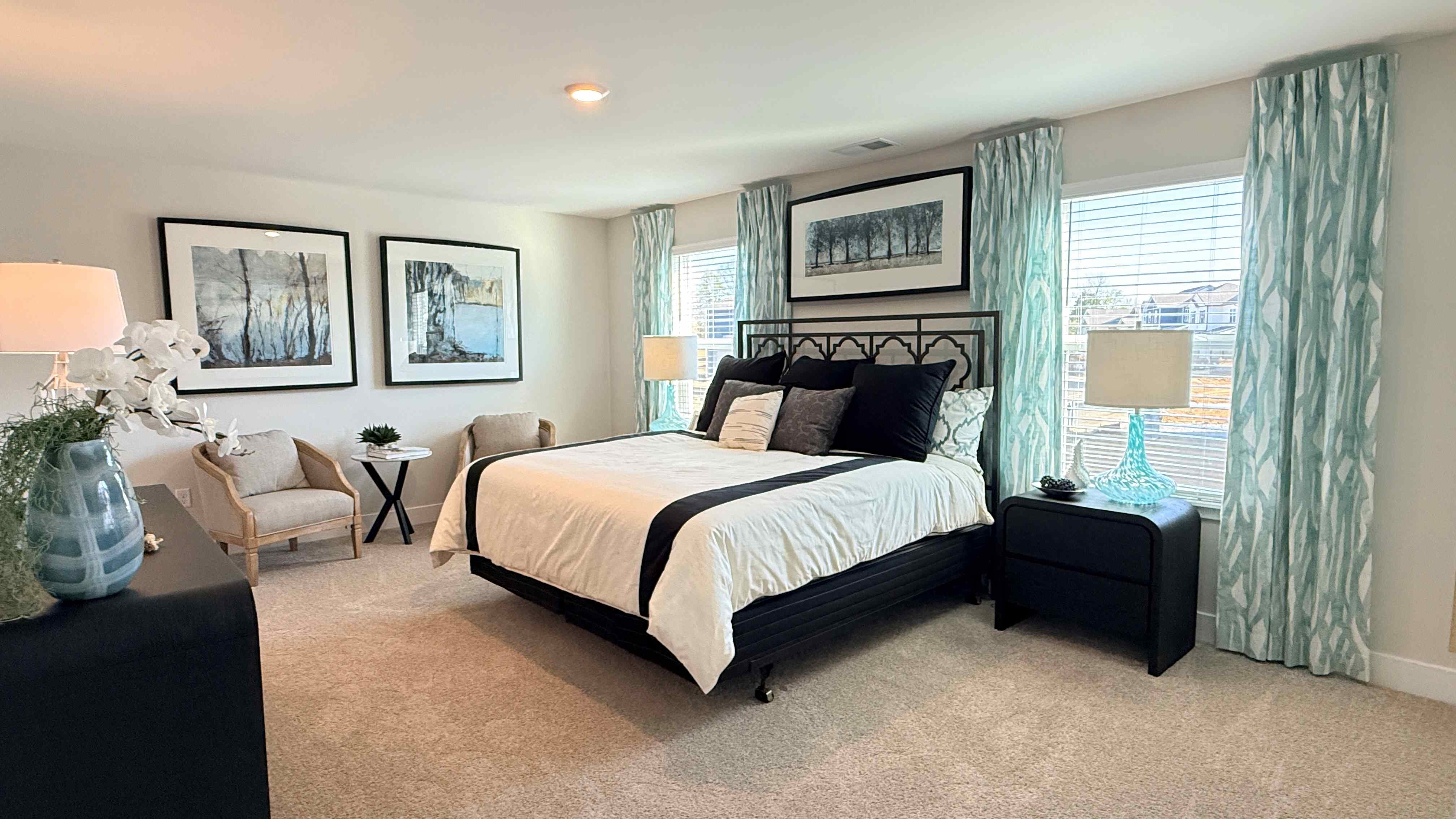 Second floor primary bedroom with two single windows, a king size bed, two accent chairs, dresser, and two nightstands with lamps.