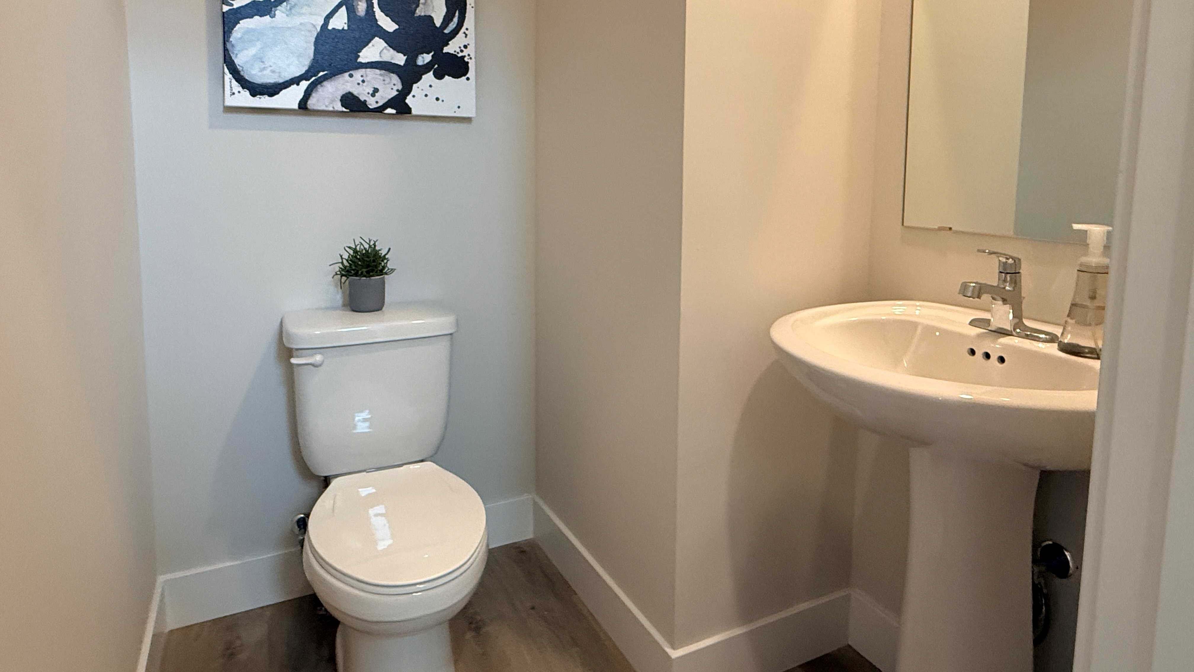 First floor half bathroom with pedestal sink and commode.