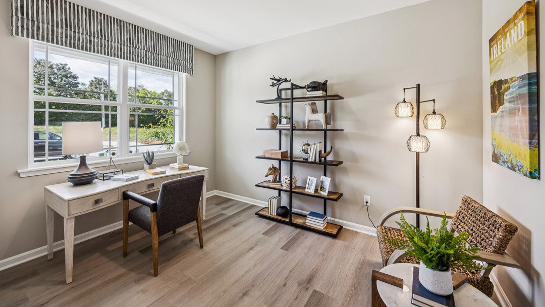 First floor flex room decorated as a home office with a double window overlooking the front yard.