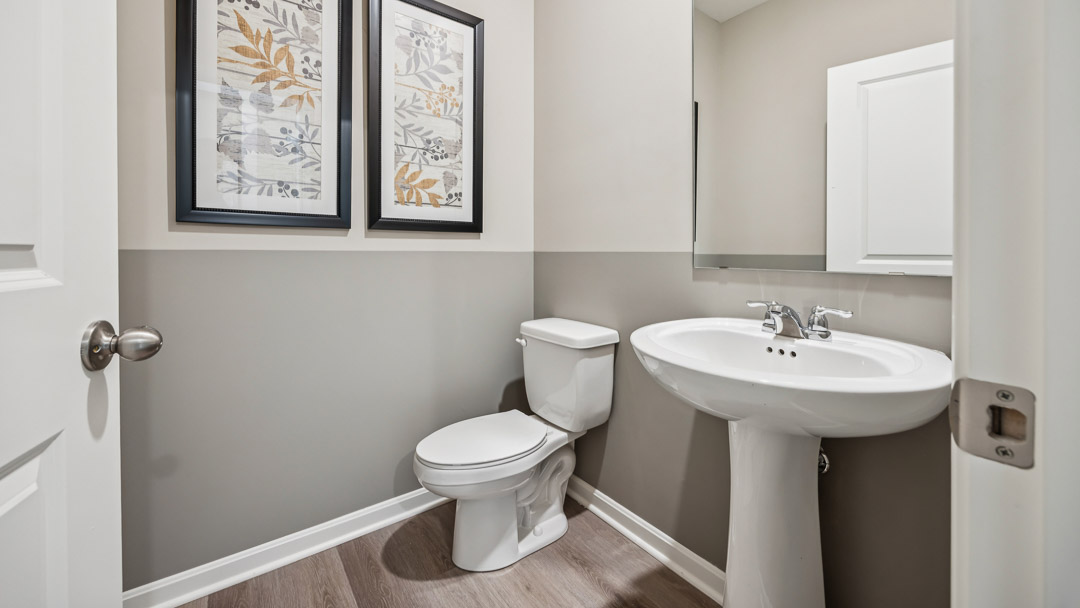 First floor half bathroom with commode and a pedestal sink with mirror above it.