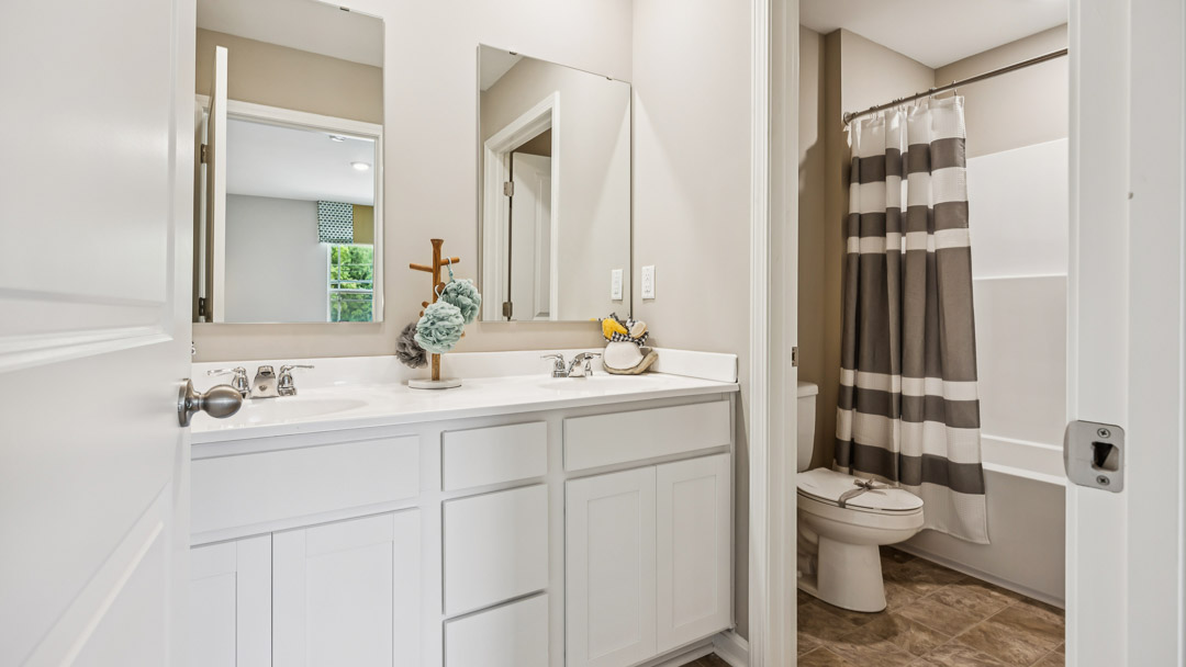 Upstairs hall bathroom with double bowl vanity, commode, and a shower/tub combo.