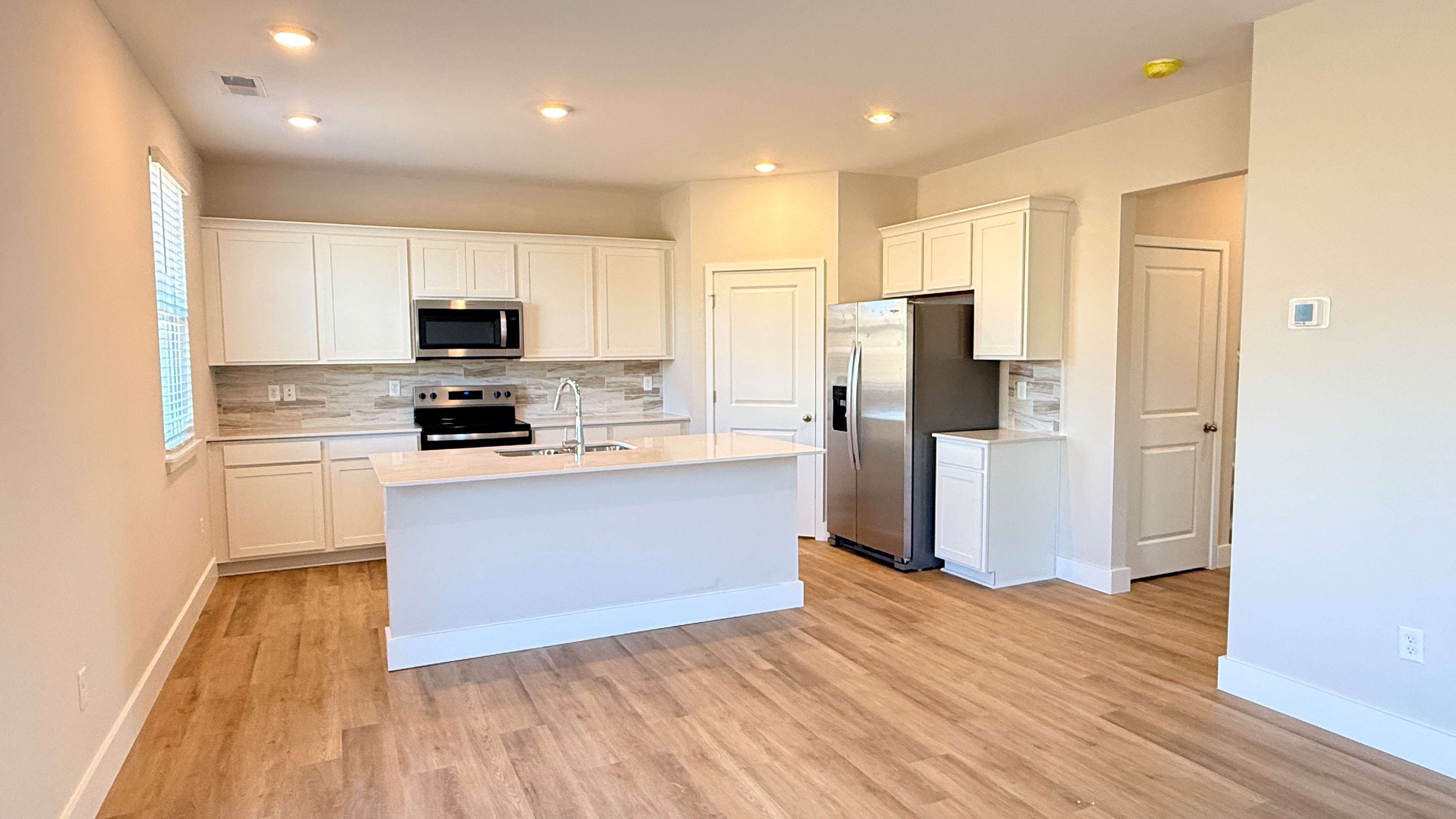 Kitchen with white cabinets, walk-in pantry, and center island.