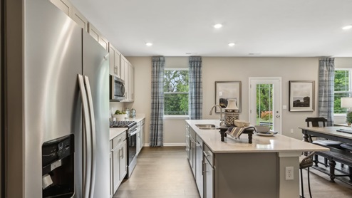 Kitchen with light cabinetry and access to living and dining areas.