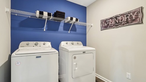 Laundry room with shelving above appliances.