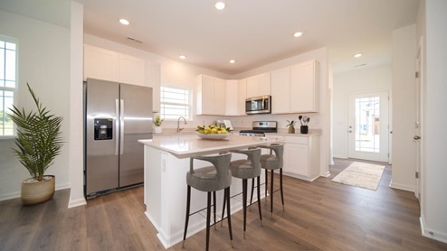 Christoph kitchen white cabinets, a kitchen island, and wood laminate flooring.