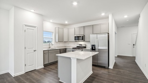 Kitchen with gray cabinets and quartz countertops.