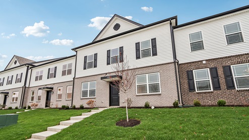 Towns at Trailside, exterior of townhomes with tan and brown bricks, off-white siding, and black shutters.