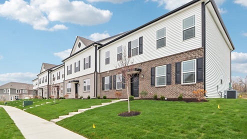 Towns at Trailside, exterior of townhomes with tan and brown bricks, off-white siding, and black shutters.