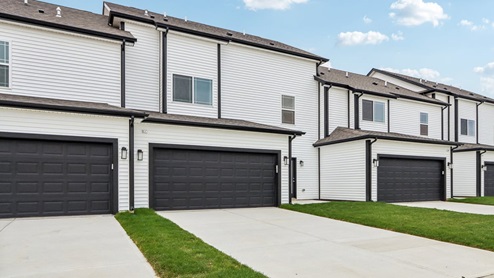 Exterior of the townhome rear with off-white siding and two-car garages per unit.