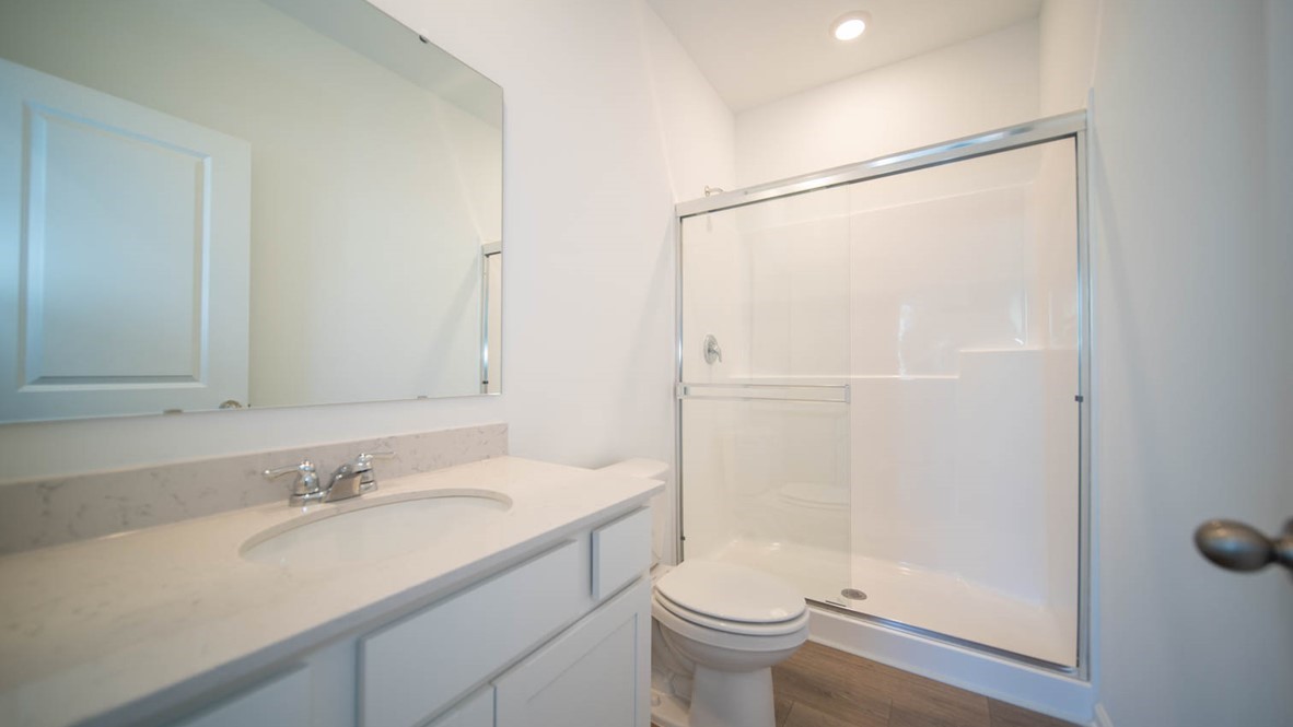 Primary bathroom with stand-up shower and vinyl flooring.
