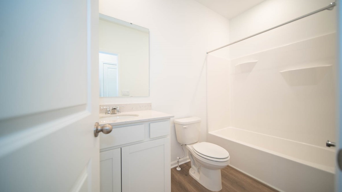Second bathroom with a bathtub and vinyl flooring.