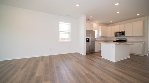 Dining area and kitchen with white cabinets, quartz countertops, and wood laminate flooring.