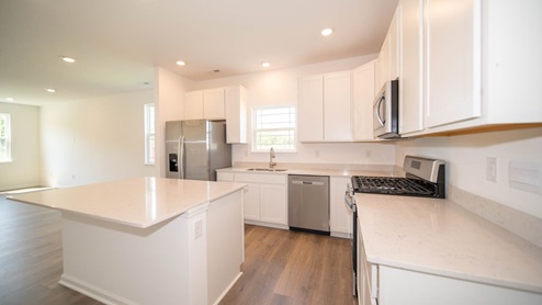 Kitchen with white cabinets, quartz countertops, and wood laminate flooring.