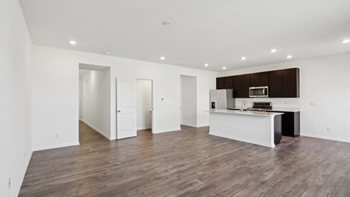 Open-concept living area and kitchen with a island and brown laminate flooring.