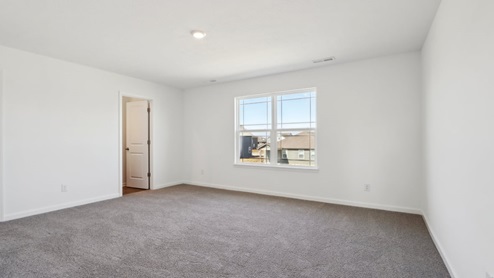 Primary bedroom with large windows and carpet flooring.