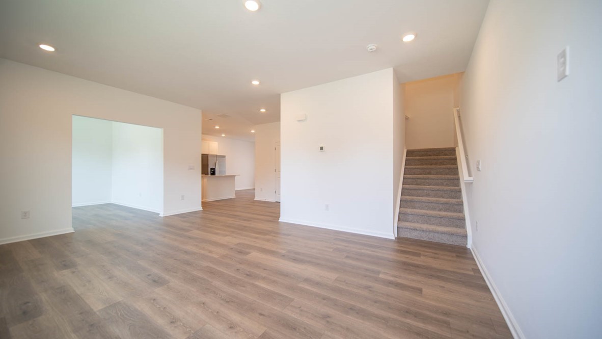 Great room interior with laminate flooring and stair access to second floor and adjacent to flex room.