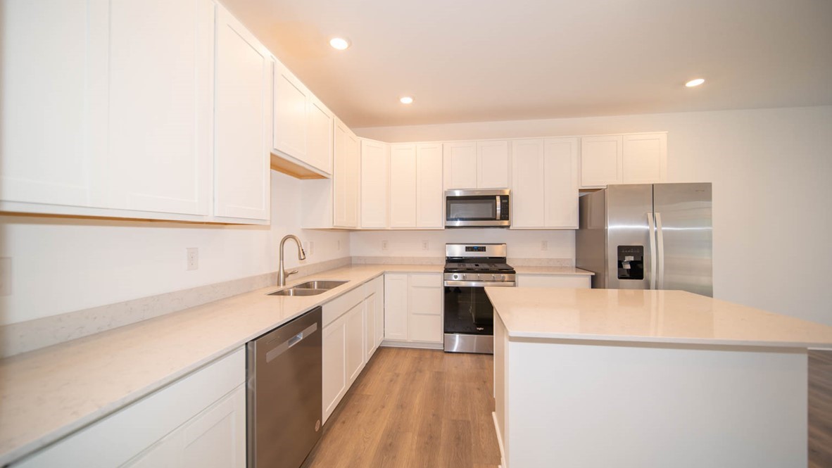 Kitchen with white cabinets, stainless steel appliances and vinyl wood flooring.