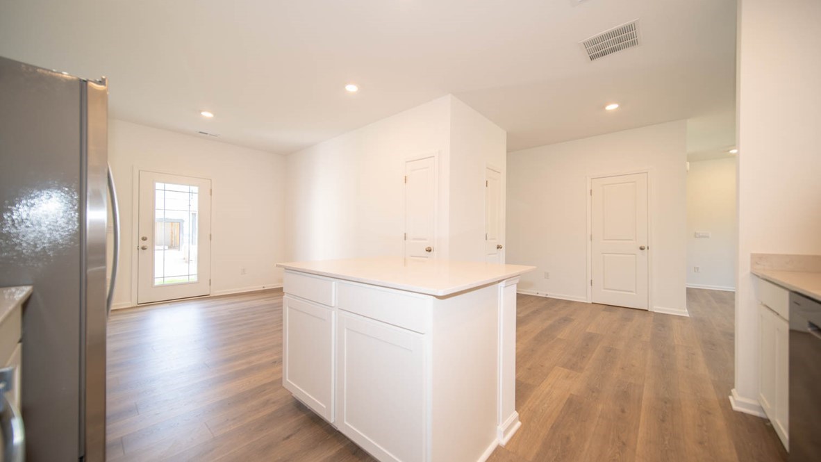 Open-concept kitchen and dining nook with vinyl wood flooring.