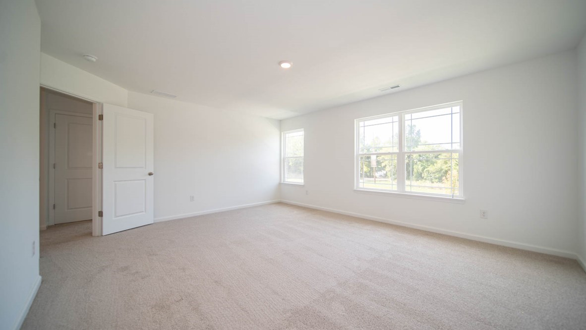 Primary bedroom with three windows and carpet flooring.