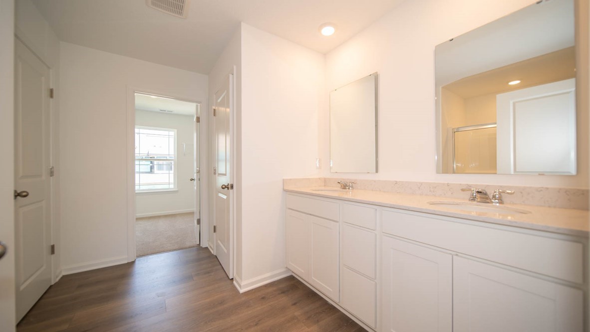 Primary bathroom with a double sink vanity, white cabinetry, and vinyl flooring.