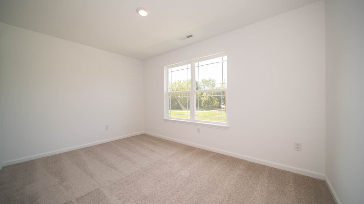 Second bedroom with a double window and carpet flooring.