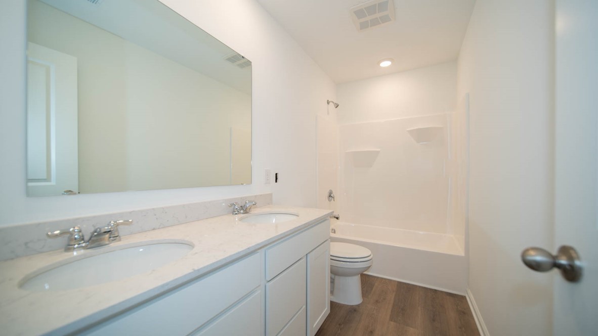 Second bathroom with a double-sink vanity, a bathtub, and vinyl flooring.