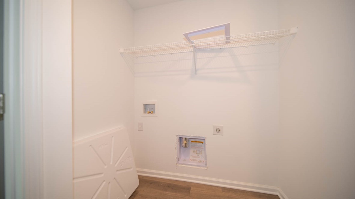 Laundry room with appliance connections and wire shelf.