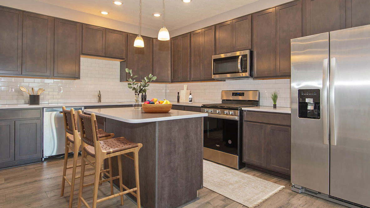 Kitchen with dark cabinets, white quartz countertoips, and an island.