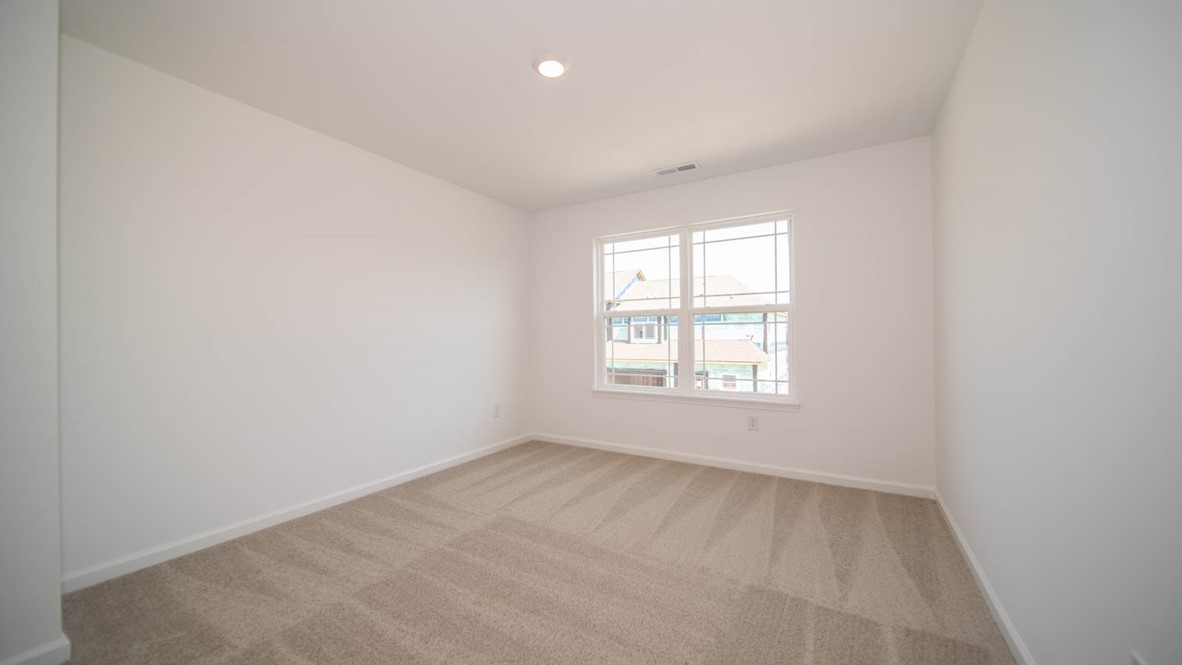 Fourth bedroom with two windows and carpet flooring.