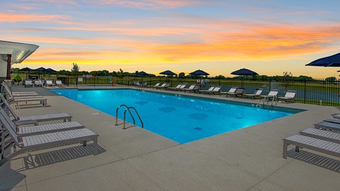 Gated outdoor pool with outdoor pool chaise chairs.