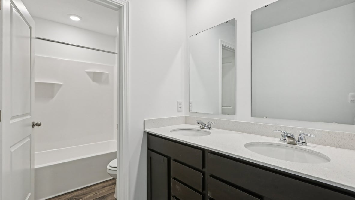 hall bathroom with dual sink vanity and private commode and tub shower