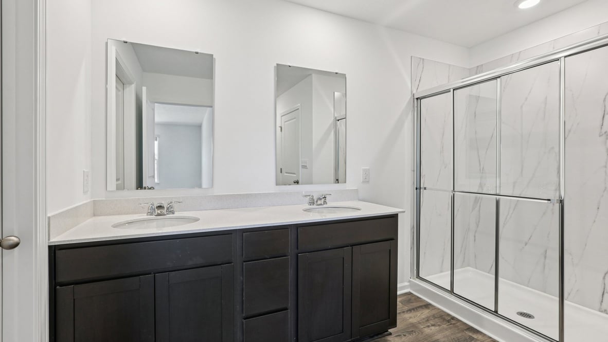 primary bathroom with dual sink vanity and shower