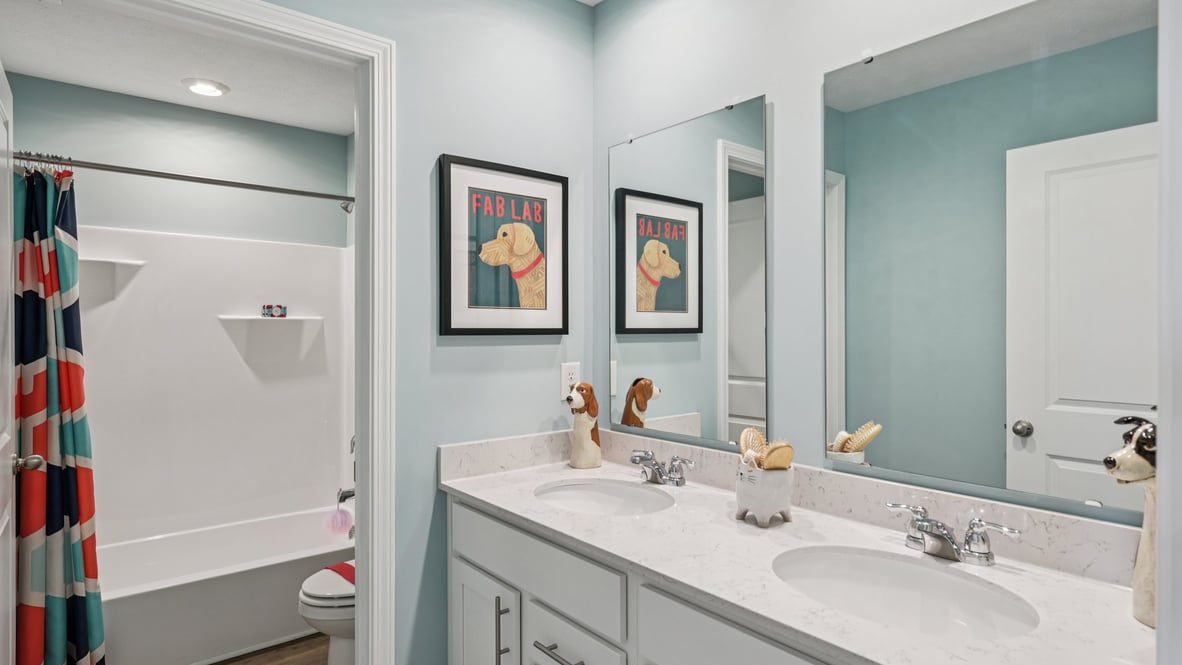 bathroom with dual vanity sinks, toilet and a shower
