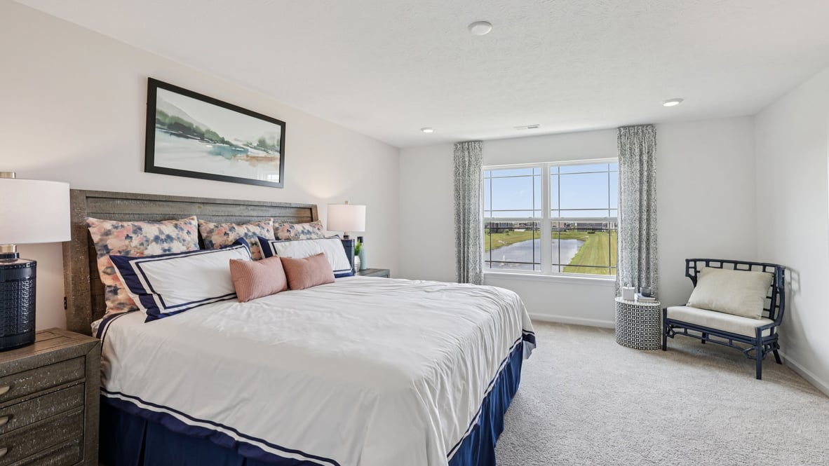 Spacious primary bedroom with beige carpet, white walls and two windows