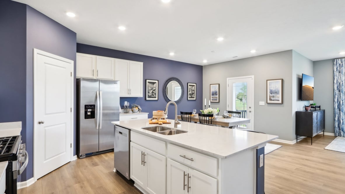 Central kitchen island designed to anchor the home with appliance suite included, sink, pantry, and multi-prep zones