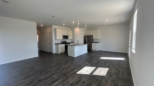 open concept great room and dining with laminate flooring