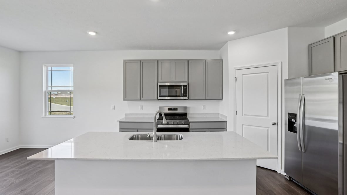 kitchen with gray cabinets, island, pantry and stainless steel appliances