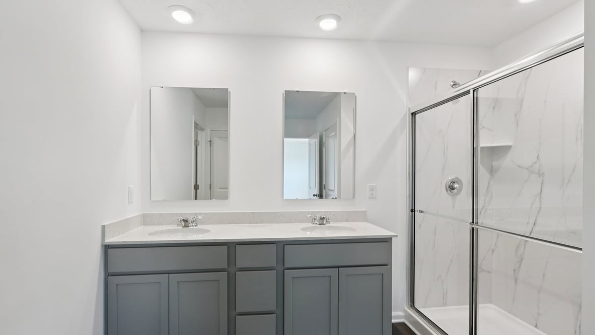 bathroom with dual vanity sinks, toilet, and a walk in shower