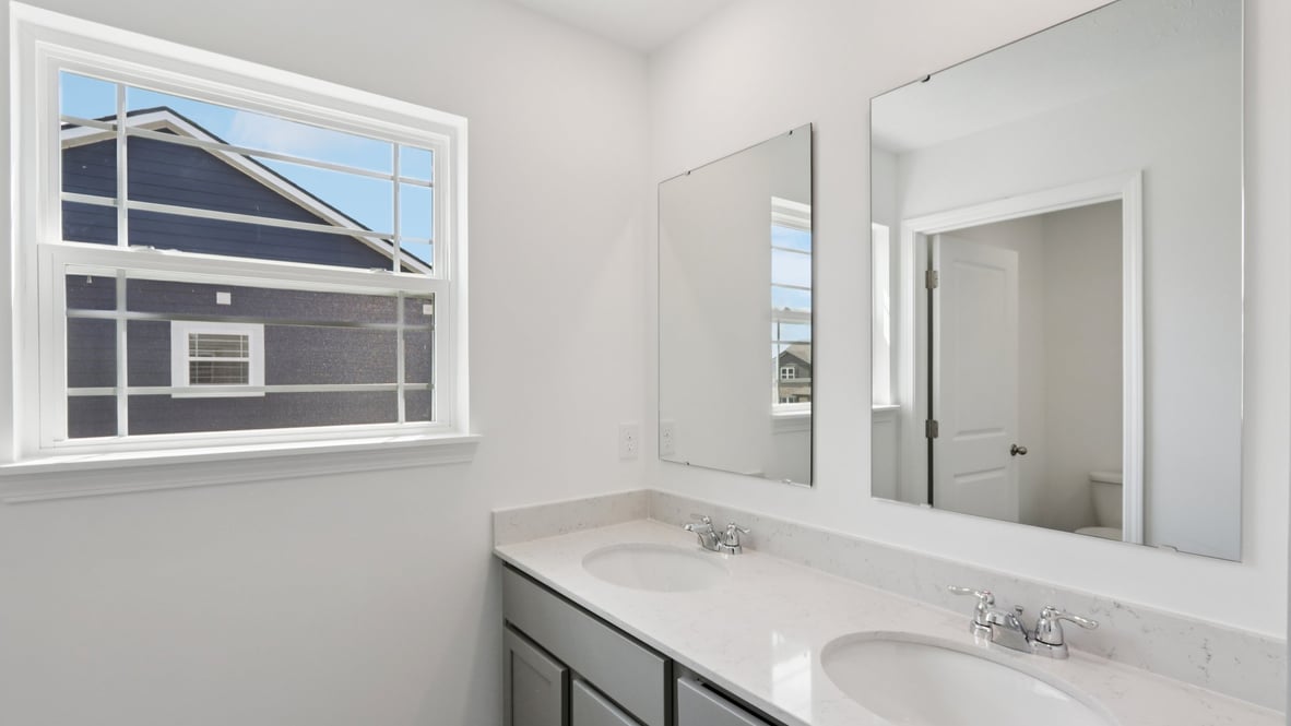 bathroom with dual vanity sinks, toilet, and a walk in shower