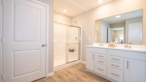primary bathroom with double bowl vanity and private commode