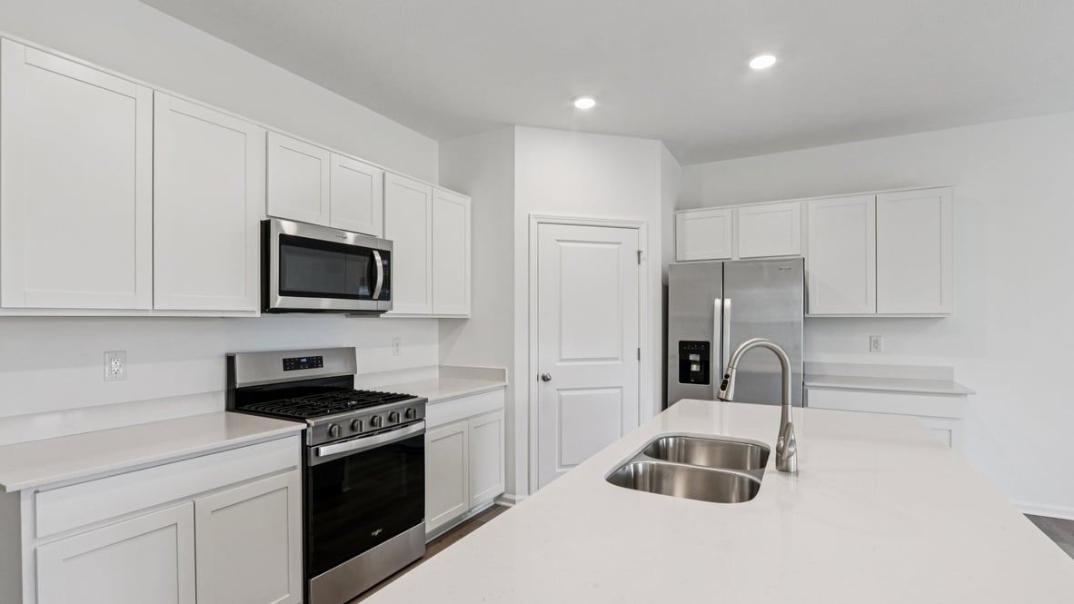 Side view of the kitchen island with sink, prep space, and a new appliance suite included Parkview Village