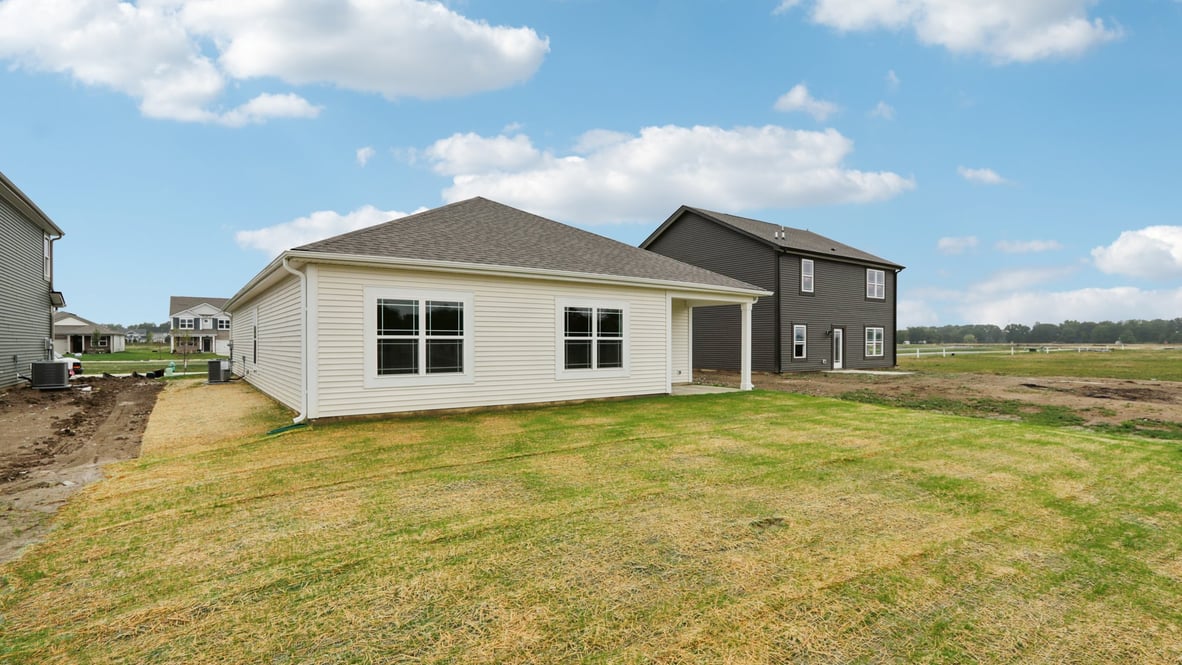 Alternate backyard angle highlighting usable green grass yard and covered patio