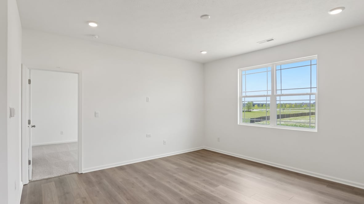 bedroom with brown flooring, white walls and a window