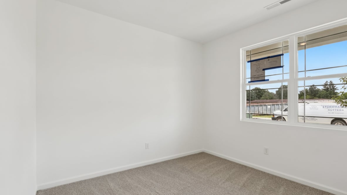 bedroom with brown flooring, white walls and a window