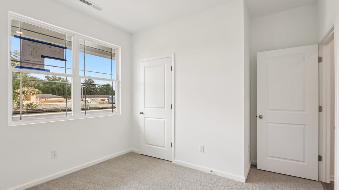 bedroom with brown flooring, white walls and a window