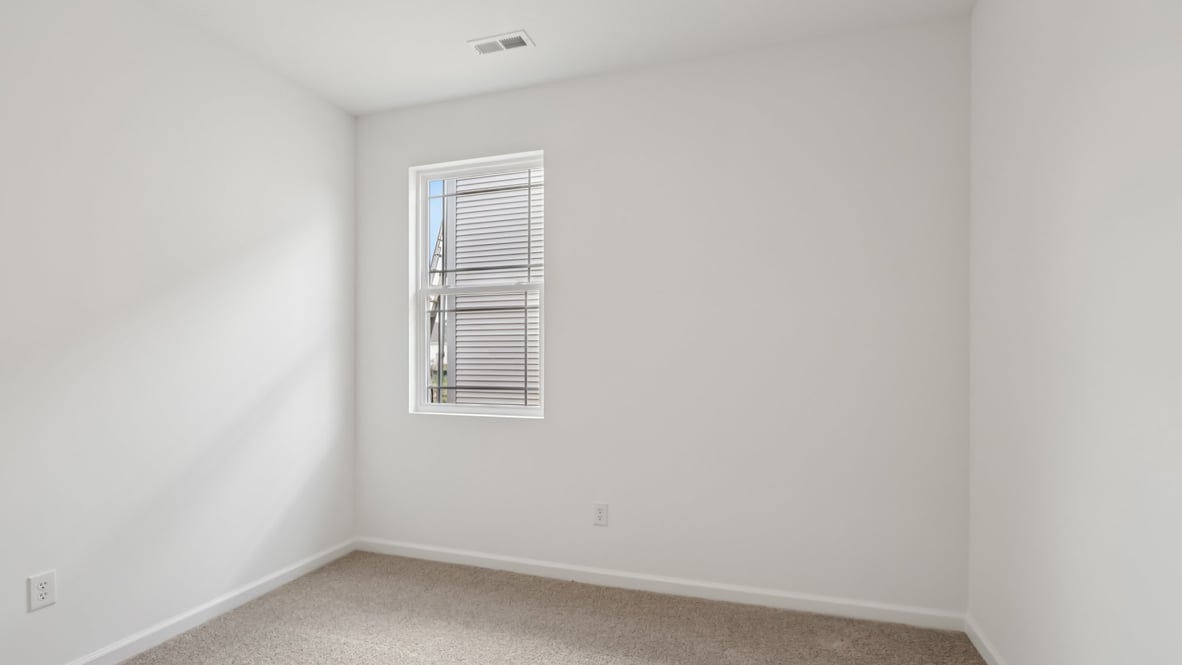 bedroom with brown flooring, white walls and a window